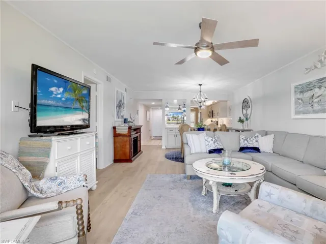 Living area featuring light wood-style laminate floors, ceiling fan, and a chandelier