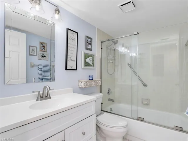 Updated bathroom featuring vanity and bath / shower combo with glass door
