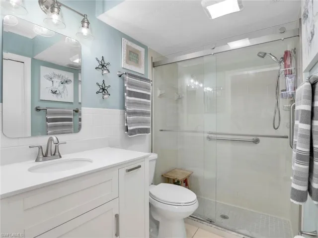 Full bath featuring tile walls, vanity, walk in shower, and tile patterned flooring