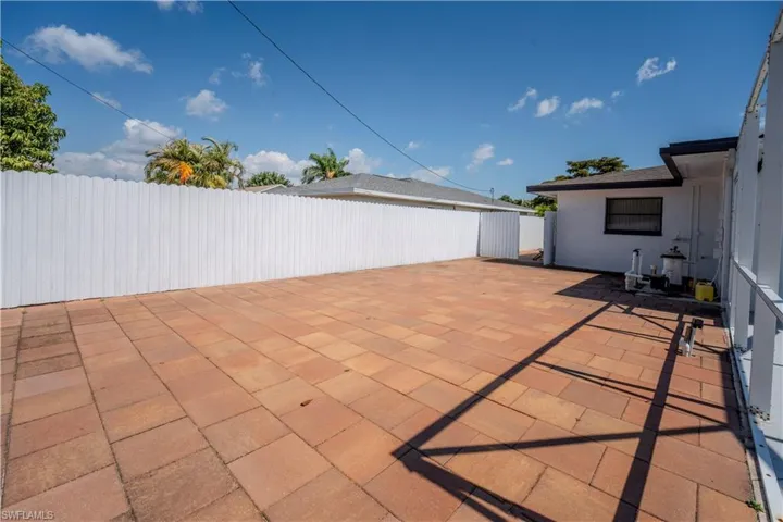 Expansive paver patio with a white privacy fence