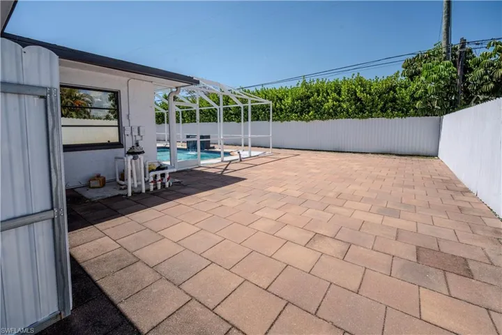 Expansive paver patio surrounding a screened pool enclosure with a water feature