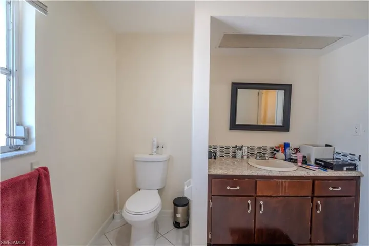2nd bathroom featuring a white toilet, tiled flooring, and a window with horizontal blinds