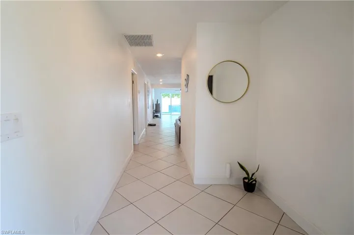 White interior walls with recessed lighting and diamond-patterned tile flooring
