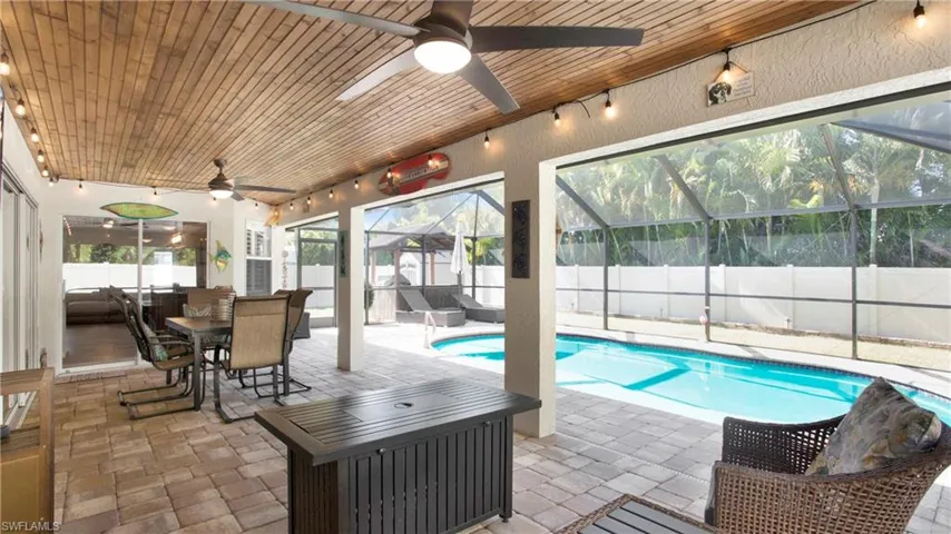 View of pool featuring ceiling fan, glass enclosure, and a patio area