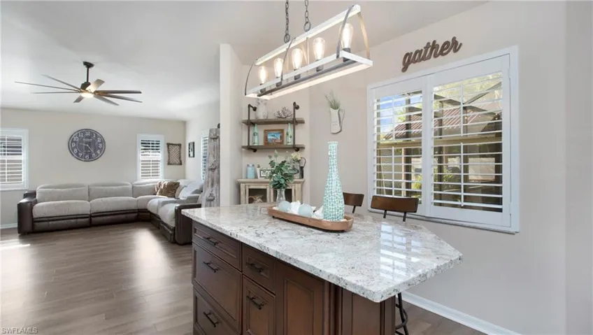 Kitchen with dark hardwood / wood-style floors, a kitchen breakfast bar, ceiling fan, decorative light fixtures, and a kitchen island