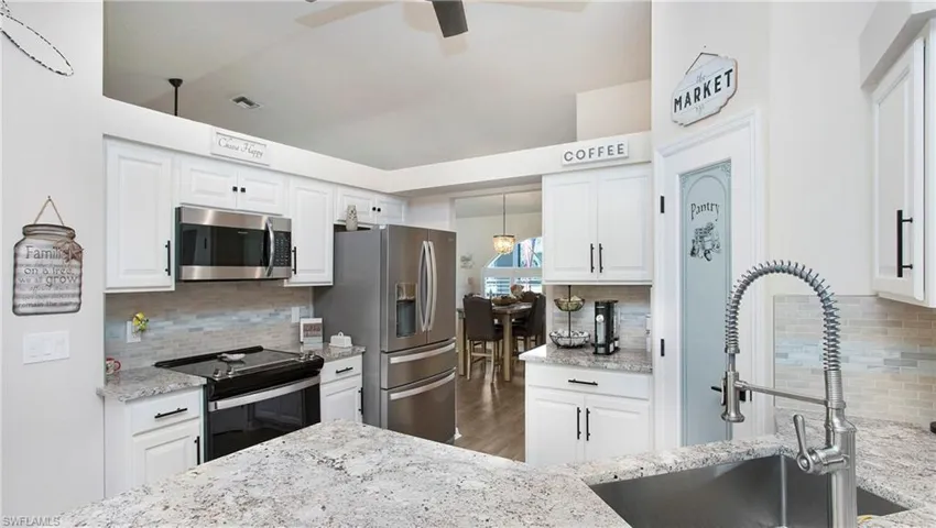 Kitchen featuring ceiling fan, light stone counters, tasteful backsplash, and appliances with stainless steel finishes