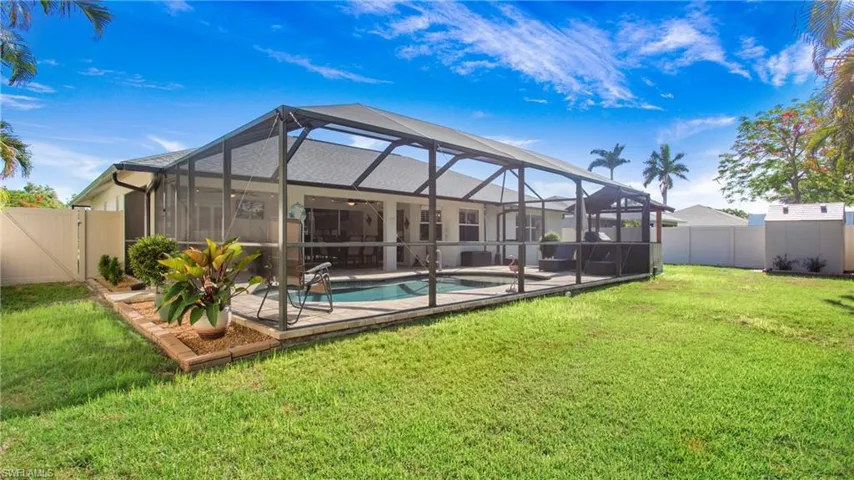 Back of house featuring a patio area, a lawn, glass enclosure, and a fenced in pool
