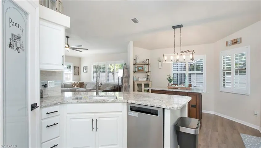 Kitchen featuring sink, ceiling fan with notable chandelier, white cabinets, and stainless steel dishwasher