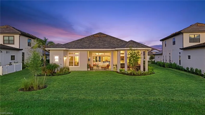 Back of house at dusk with a patio area, a lawn, and stucco siding