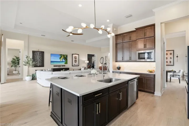 Kitchen with a kitchen breakfast bar, pendant lighting, light stone counters, open floor plan, and light wood-type flooring