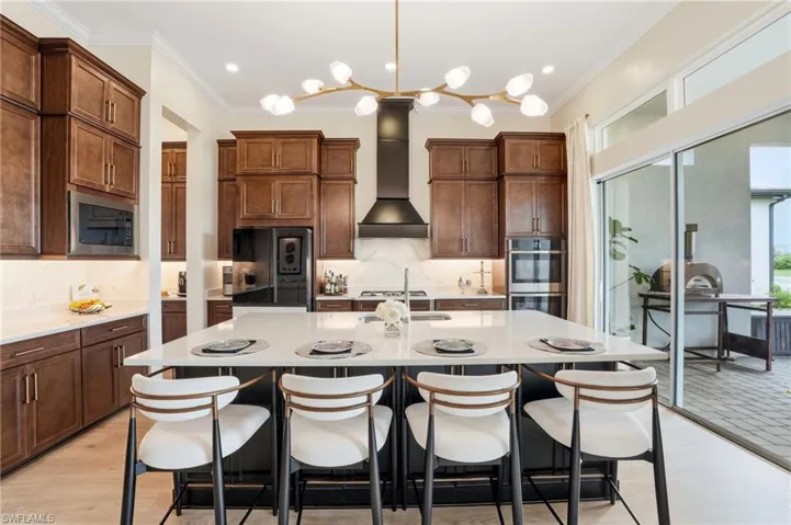 Kitchen with a kitchen breakfast bar, decorative light fixtures, backsplash, light stone countertops, and crown molding
