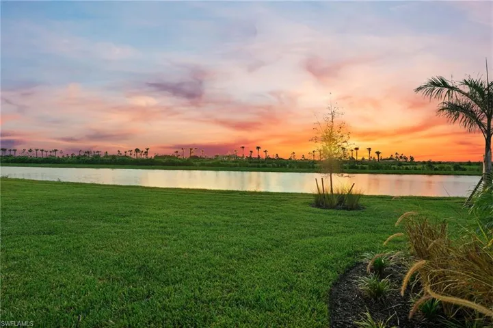 Yard at dusk featuring a water view and a lawn