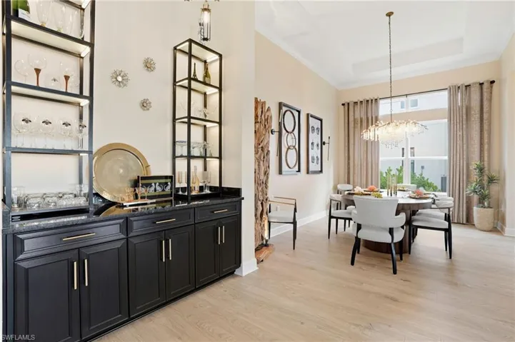 Dining space with light wood-style floors, crown molding, a raised ceiling, and a chandelier