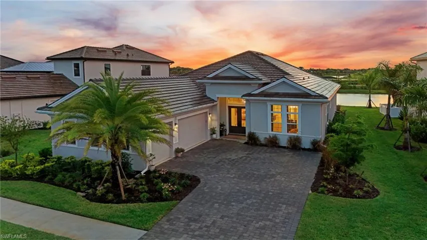 View of front of house featuring a front lawn, decorative driveway, stucco siding, and a garage