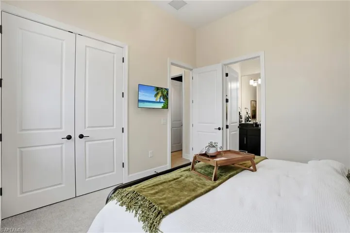 Bedroom with a closet, light colored carpet, and ensuite bathroom
