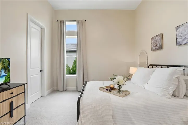 Bedroom with light colored carpet and baseboards