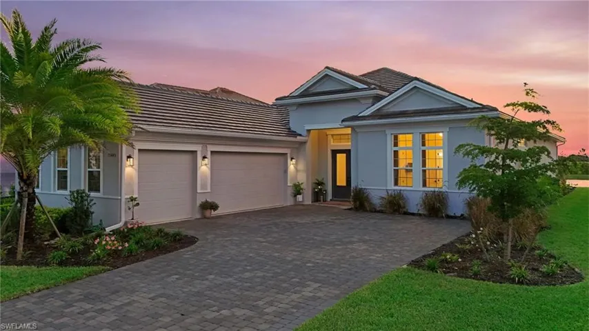 Ranch-style home with an attached garage, stucco siding, decorative driveway, and a front yard