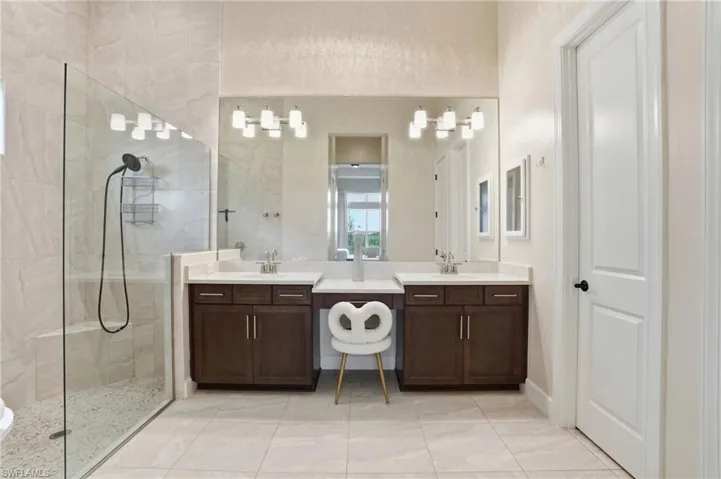 Bathroom with walk in shower, vanity, and light tile patterned flooring