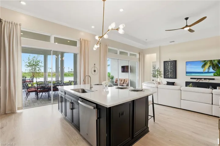 Kitchen with dark cabinetry, pendant lighting, open floor plan, a kitchen island with sink, and light wood-style flooring