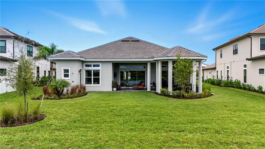 Rear view of house with a lawn, stucco siding, a patio, and a tiled roof