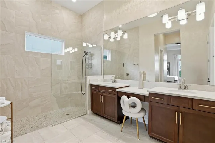 Bathroom featuring a walk in shower, vanity, and light tile patterned flooring