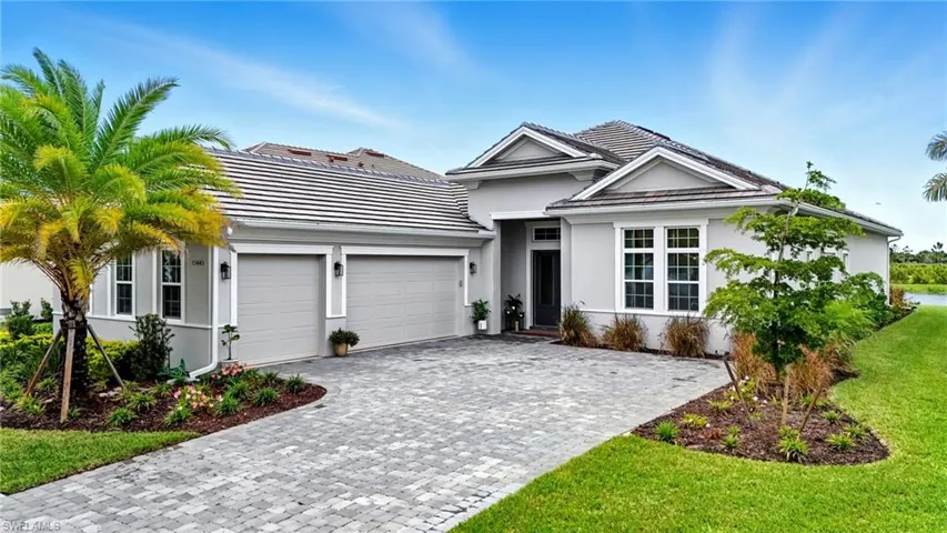 Ranch-style home featuring decorative driveway, stucco siding, an attached garage, and a front yard