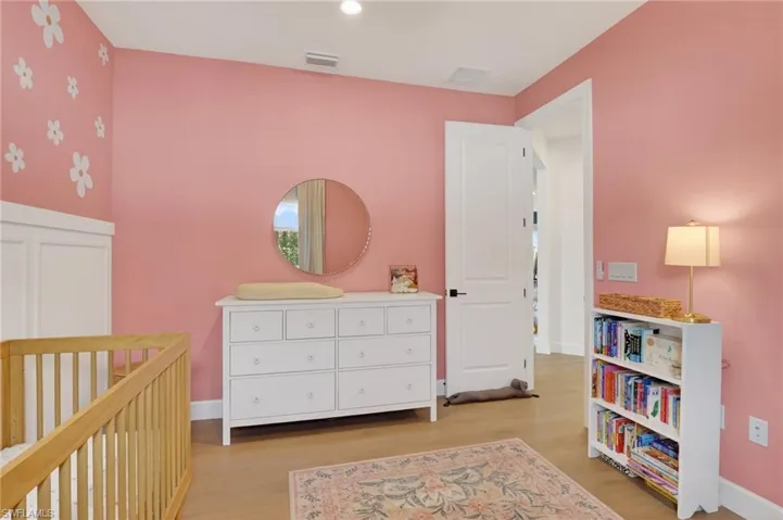 Interior room featuring wood-finish flooring and a white paneled door with dark hardware