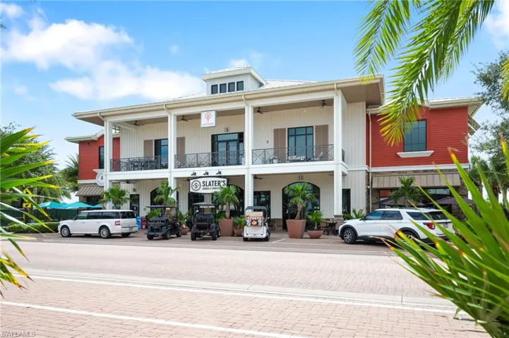 Two-story commercial building featuring red and white vertical siding, prominent balconies with black railings, and a ground-floor awning
