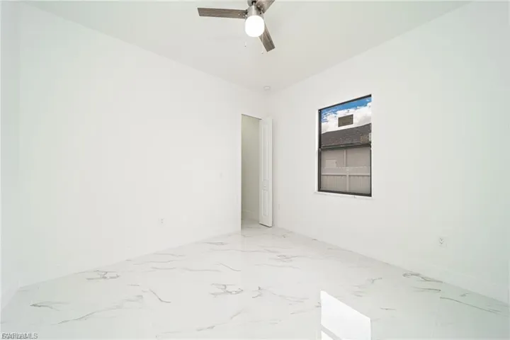 Unfurnished room featuring light marble finish floors and ceiling fan