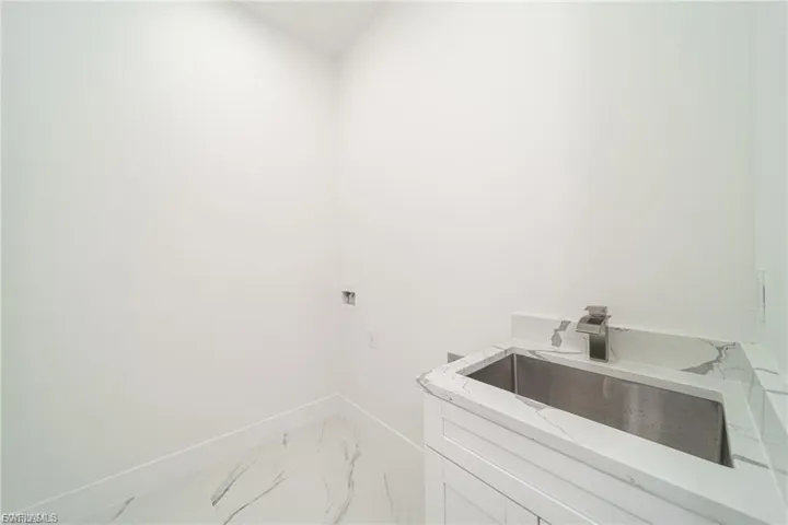 Laundry area featuring light marble finish floors, washer hookup, and cabinet space