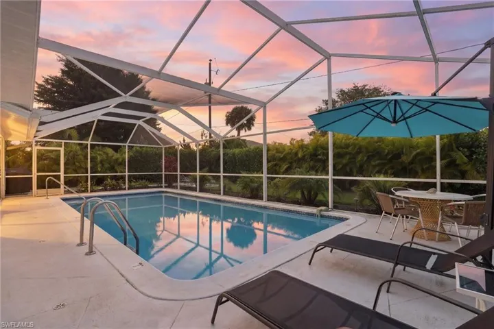Outdoor pool with a sunroom, glass enclosure, a patio area, and outdoor dining area