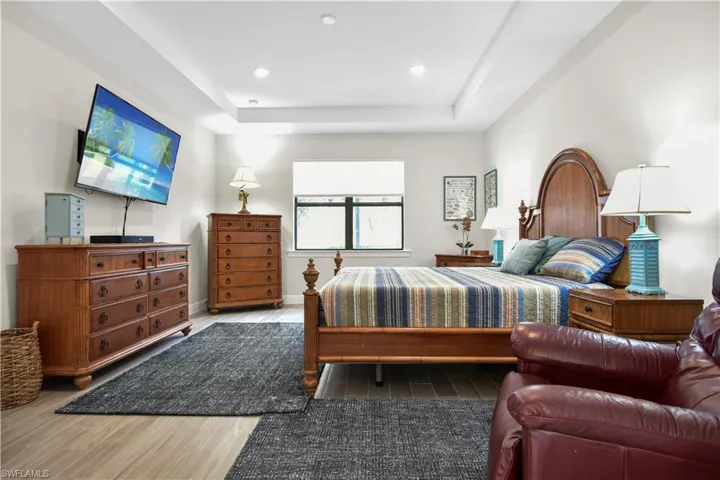 Primary bedroom with plank tile flooring and a tray ceiling