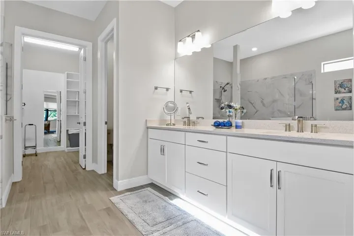 Spacious primary bath with large walk-in closet, dual sinks, shower and separate water closet.