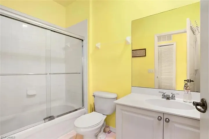 Full bathroom with vanity, toilet, and enclosed tub / shower combo