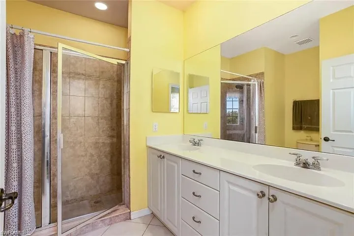 Bathroom with tile patterned flooring, double vanity, toilet, and curtained shower