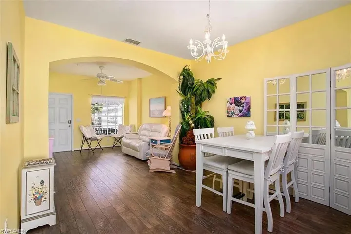 Dining area with ceiling fan with notable chandelier and dark hardwood / wood-style flooring