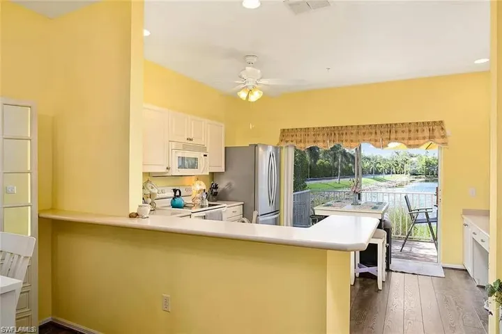 Kitchen with white appliances, wood-type flooring, plenty of natural light, and kitchen peninsula