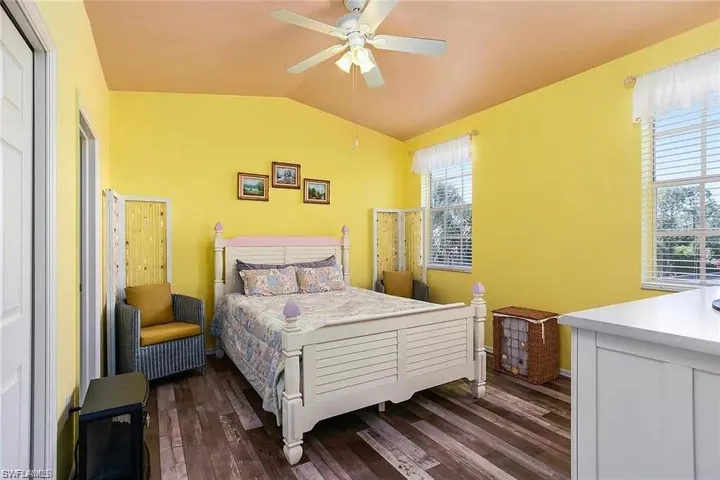Bedroom featuring ceiling fan, vaulted ceiling, wood-type flooring, and multiple windows