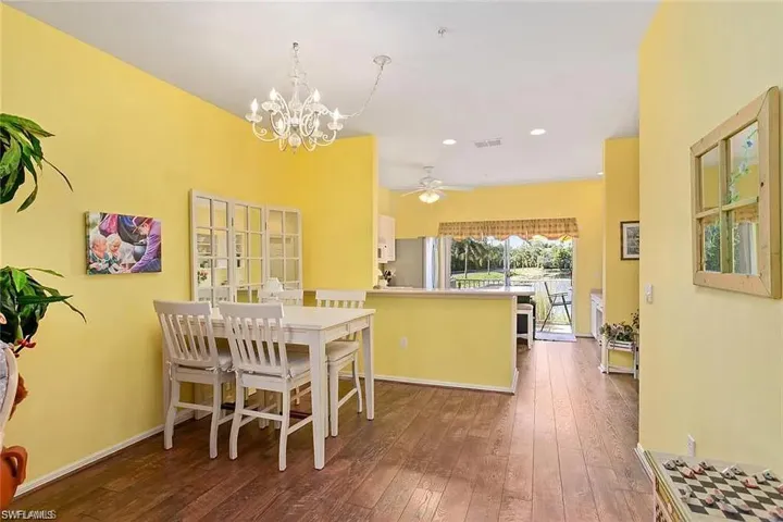Dining space with ceiling fan with notable chandelier and hardwood / wood-style flooring