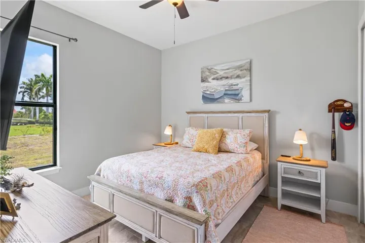 Another lovely guest bedroom featuring multiple windows and ceiling fan