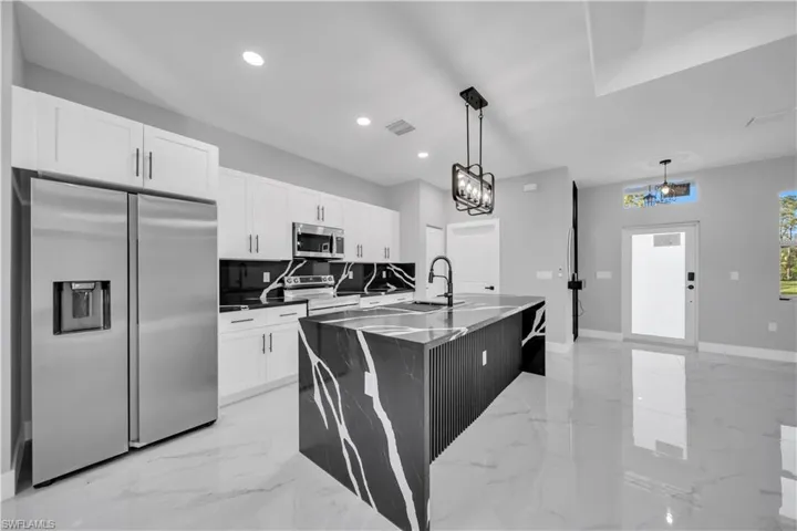 Modern kitchen featuring a striking black and white veined island with an integrated sink and black faucet