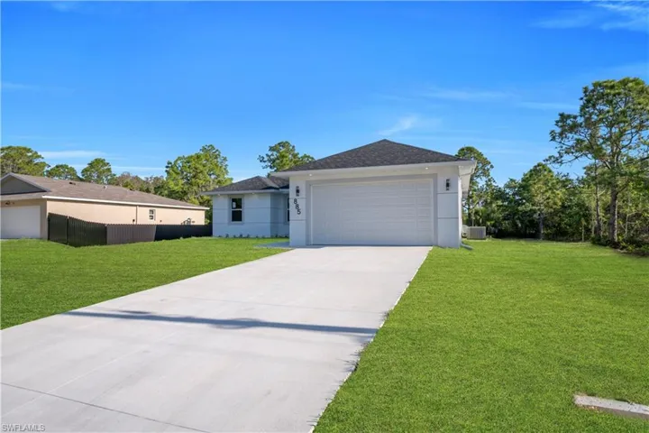 Modern residence with a two-car garage, concrete driveway, and expansive green lawn