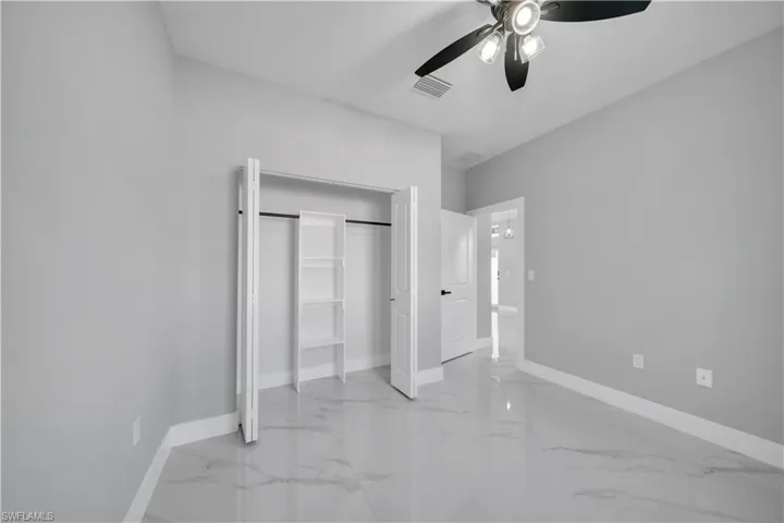Spacious room featuring light gray walls, large format marble-look tile flooring, and white baseboards