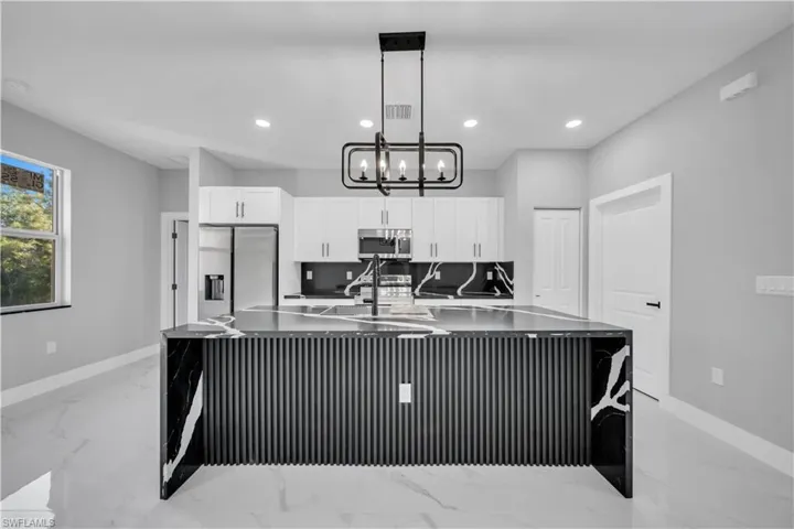 Sleek kitchen featuring a waterfall island with fluted paneling and dark stone with white veining