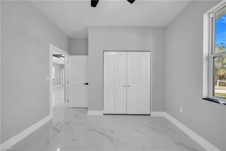 Room featuring bright white tile flooring with gray veining, light gray walls, and white baseboards