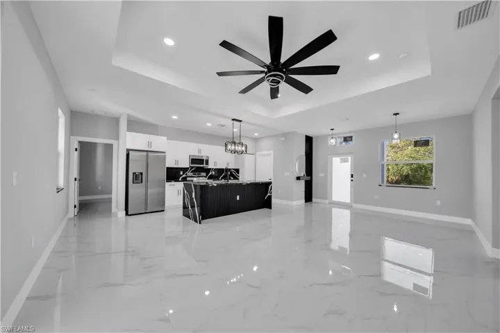 Open-concept living area featuring large format polished tile flooring and a tray ceiling with recessed lighting