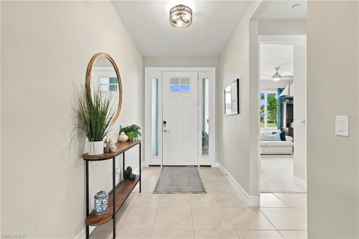 Entryway featuring neutral tile flooring, a white front door with glass paneling, two vertical sidelights, and a flush-mount drum ceiling light
