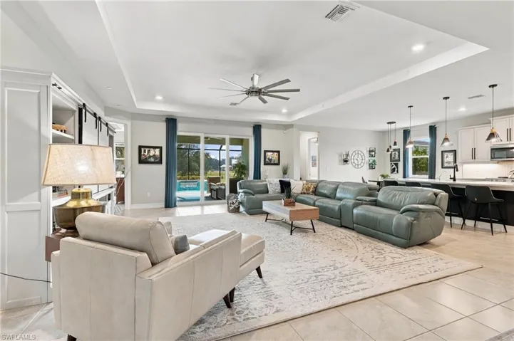 Open-concept interior featuring a 10' tray ceiling, recessed lighting, and a large kitchen island with pendant lighting