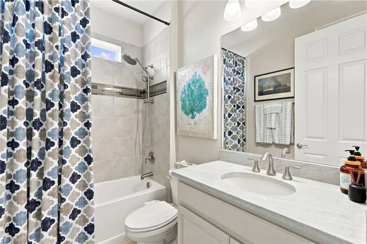 Bathroom featuring a vanity with a light-toned countertop, undermount sink, brushed nickel faucet, large wall-mounted mirror, bidet, and a tub-shower combination with tile surround and inlay detail