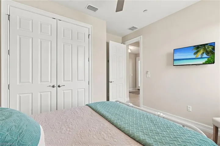 Bedroom featuring white six-panel closet doors with brushed nickel hardware, a matching interior door, and a ceiling fan with light